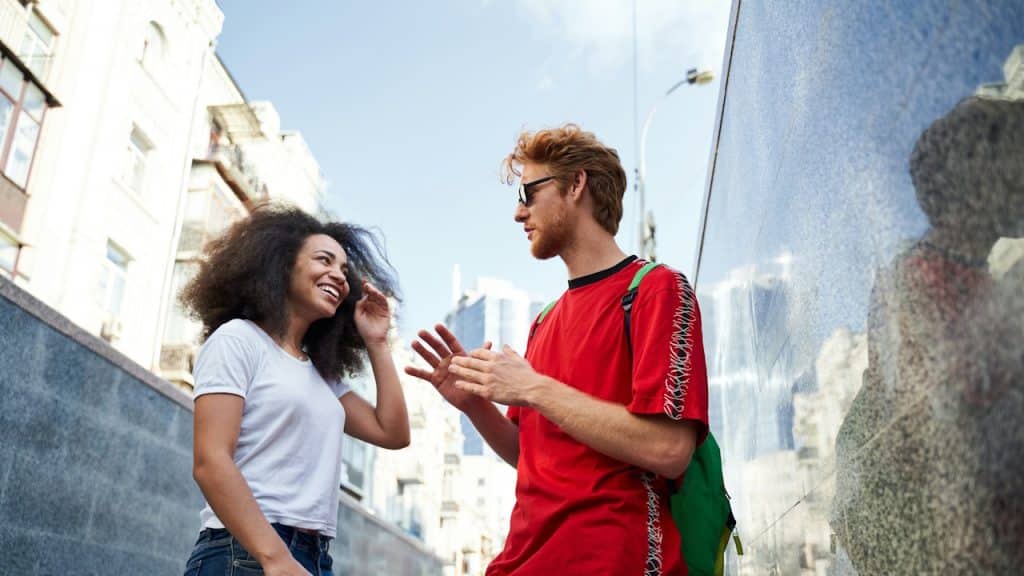 A happy interracial couple talking and smiling on a city street.