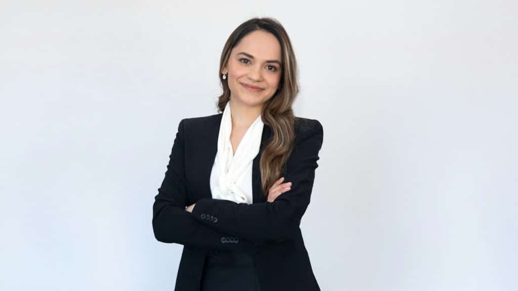 A woman lawyer standing with her arms crossed across her chest and smiling.