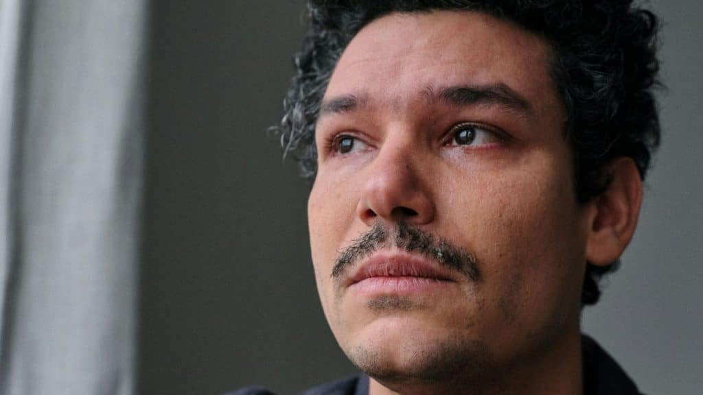Close-up of a distressed man with a mustache looking up with tears in his eyes.