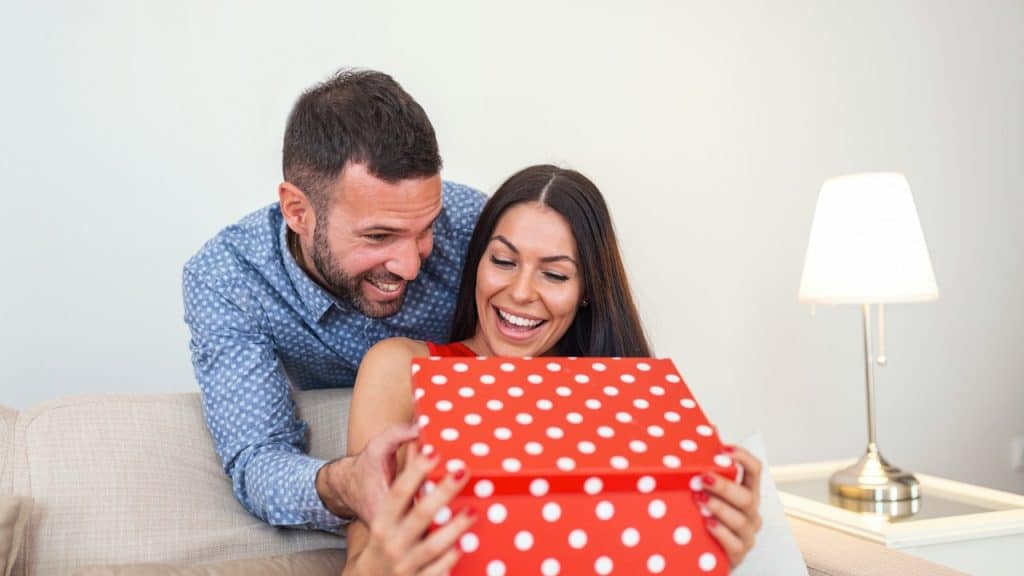 A young man giving a gift box to his girlfriend on Valentine's Day.