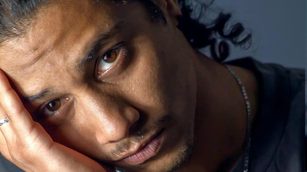A man looking upset and holding his hand upto his cheek.