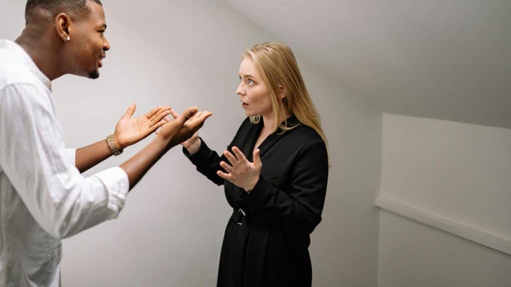 A man and woman standing and arguing with raised hands.