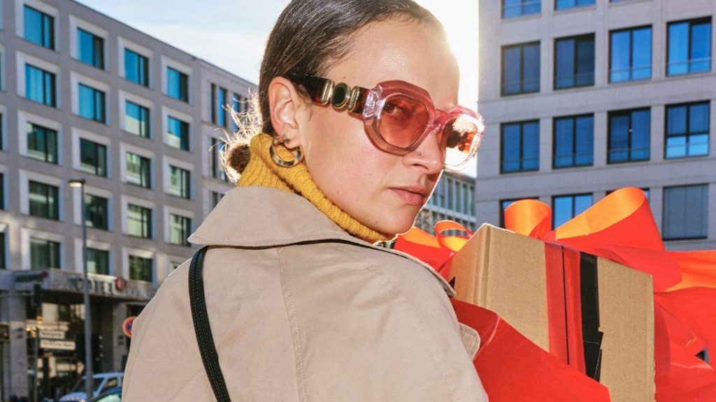 A woman carrying gift boxes on a city street.