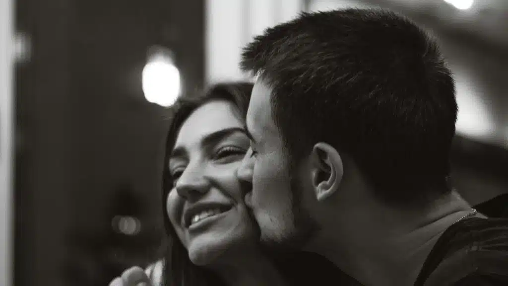 A man kissing a smiling woman’s cheek.