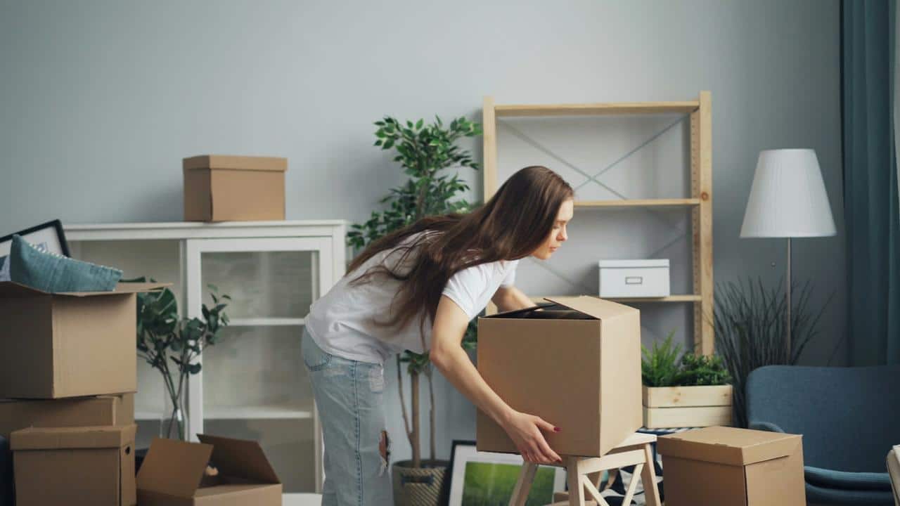 A woman packing cardboard boxes in a room.
