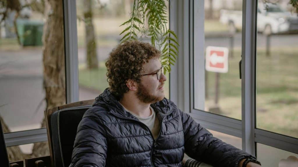 A man sitting indoors looking out a window.