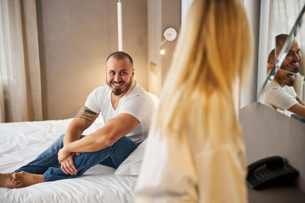 A man at the bed just looking at the woman