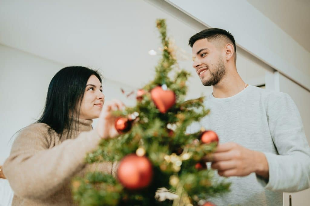 A couple decorating a Christmas tree.