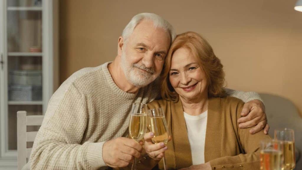 A smiling couple sitting close together and clinking glasses.