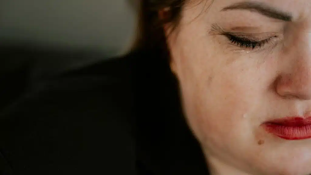 Close-up of a woman's face with a tear rolling down her cheek.