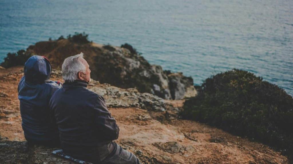 An older couple sitting by the sea.