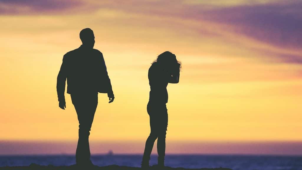 A silhouette of a man and woman under a yellow sky.