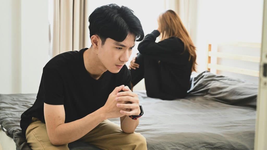 A man and woman sitting on a bed having relationship problems.