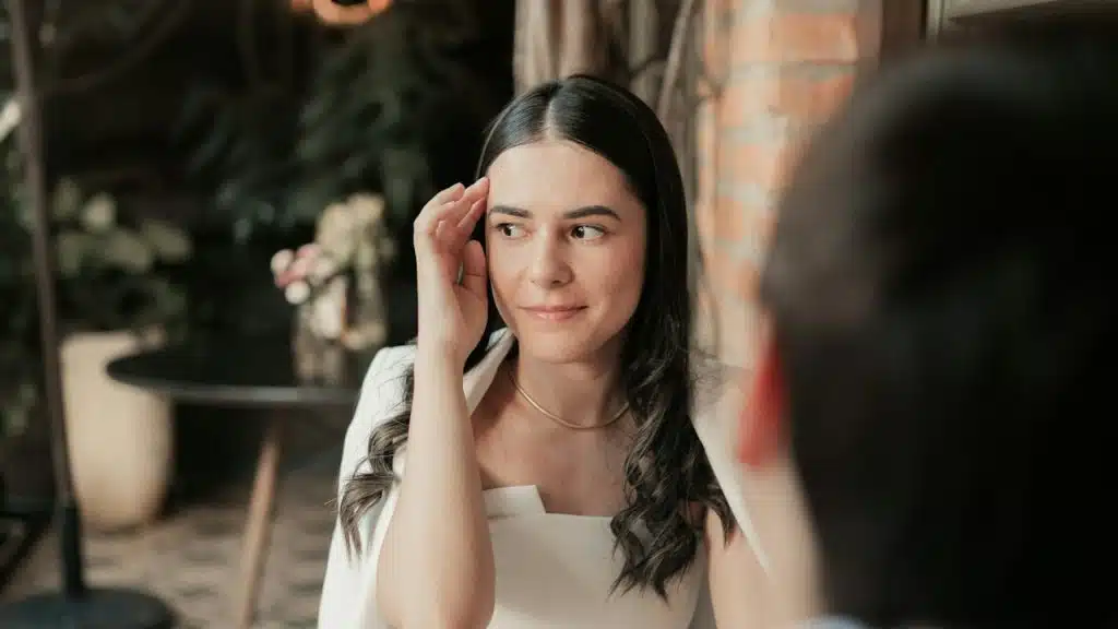 A woman playing with her hair while sitting in a restaurant with her boyfriend.