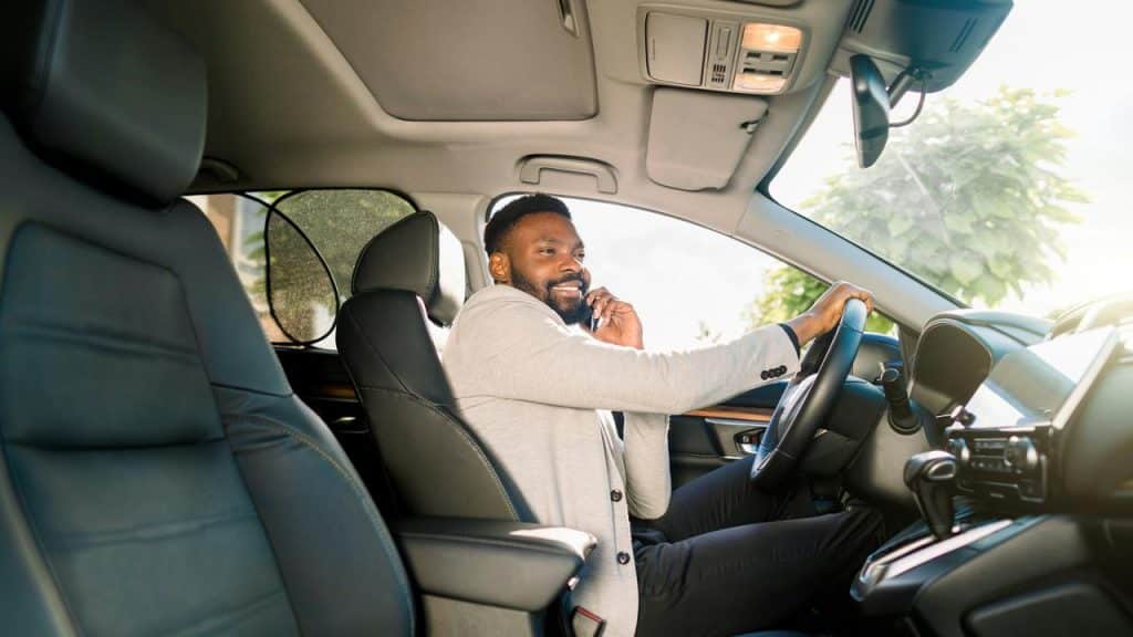 A person sitting in a car and talking on a smartphone while driving.