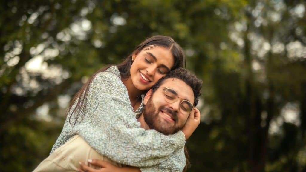 A man wearing glasses is carrying a woman on his back.