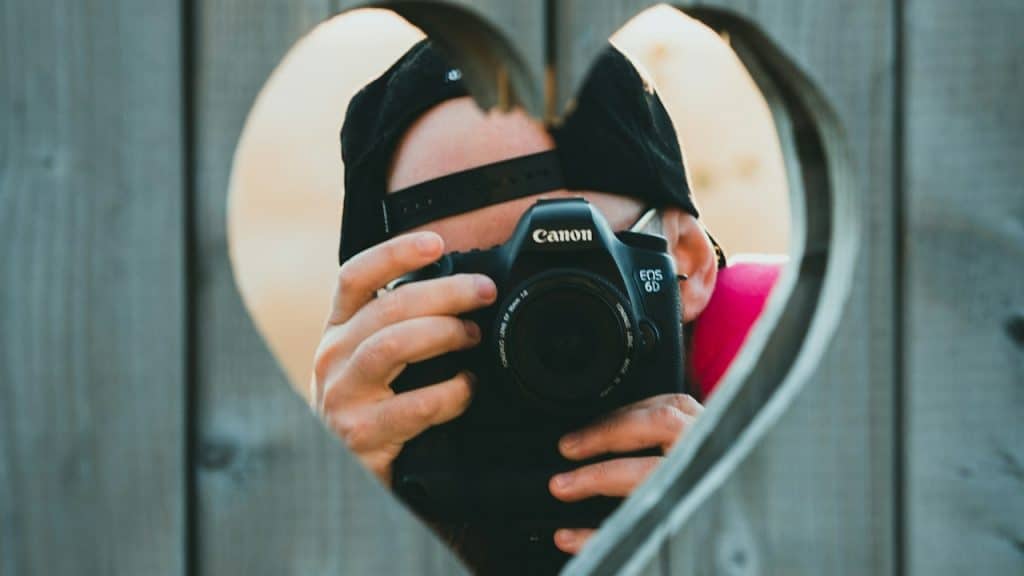 A person holding a camera in front of a heart.