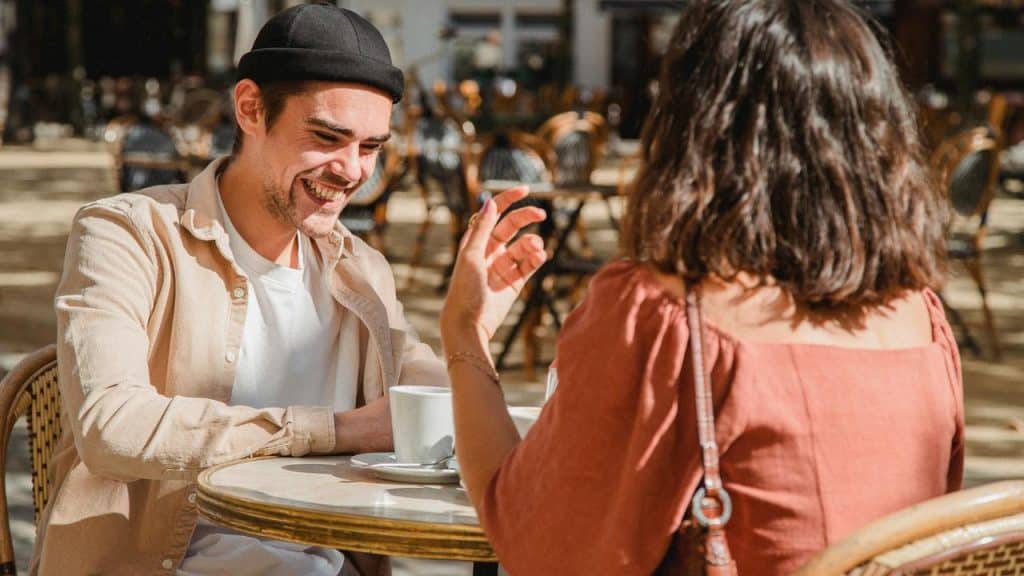 A man and woman smiling and talking at an outdoor café.