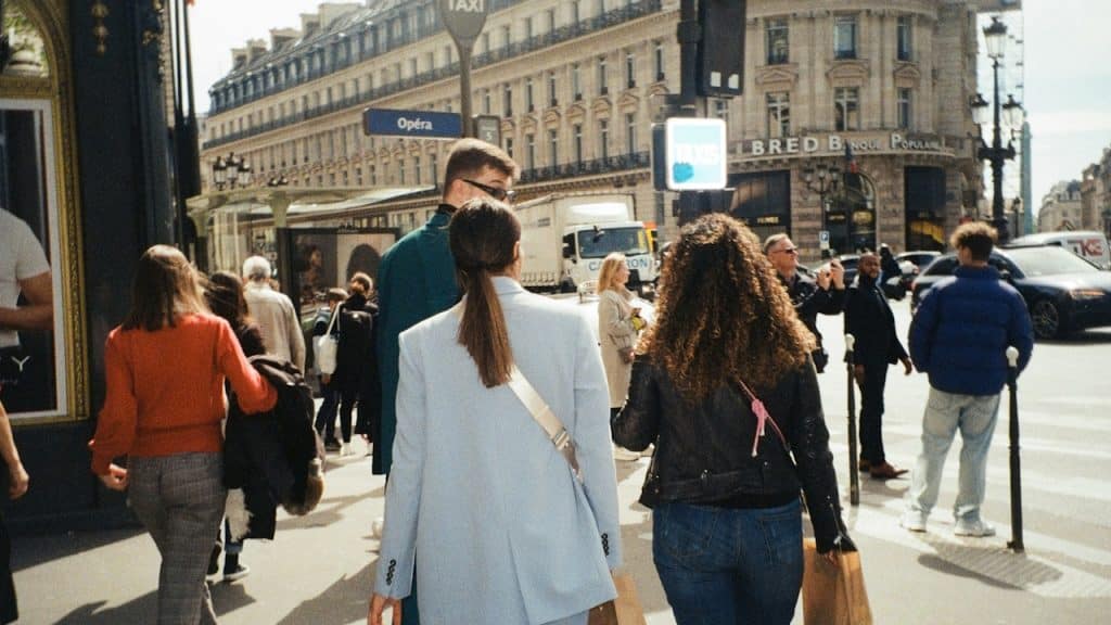 A group of people walking down a street next to tall buildings.