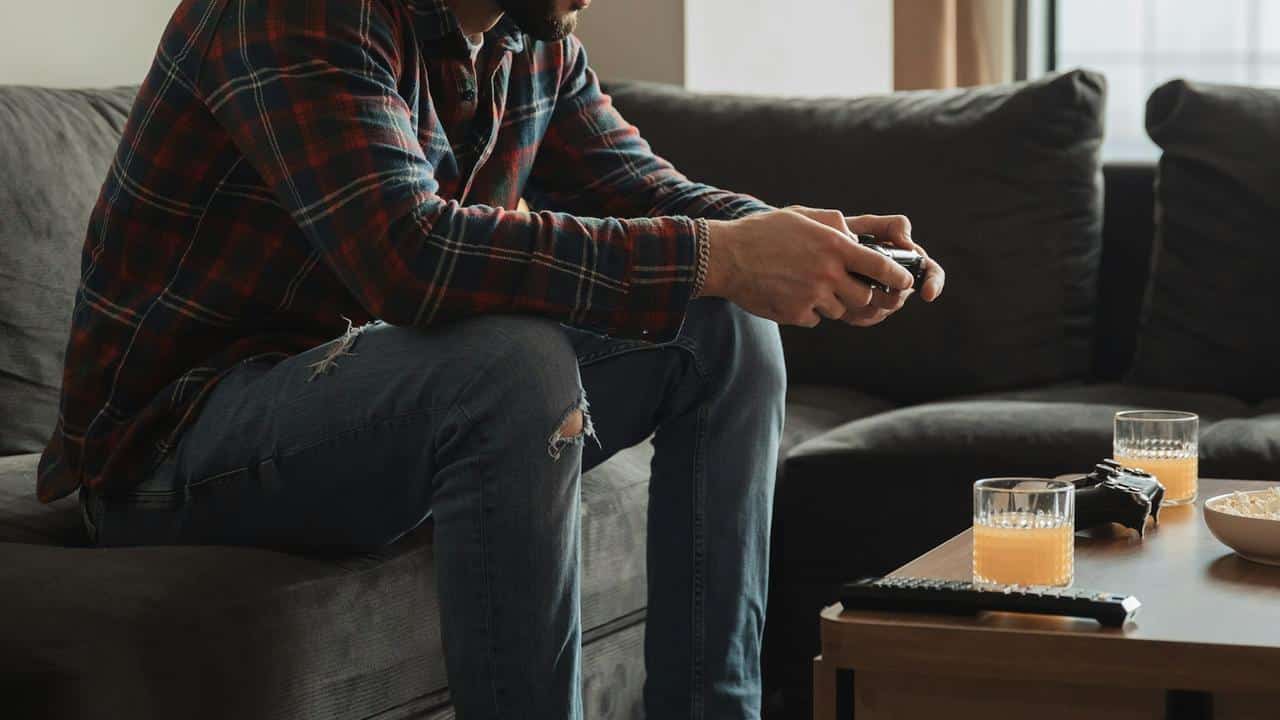 A man sitting on a couch, holding a game controller,.