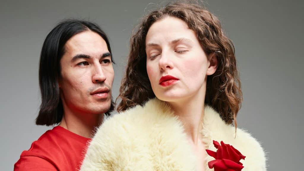 A man and a woman holding a rose standing close to each other.