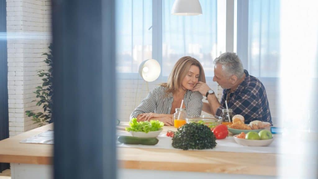 A mature couple sharing a tender moment at the breakfast table.