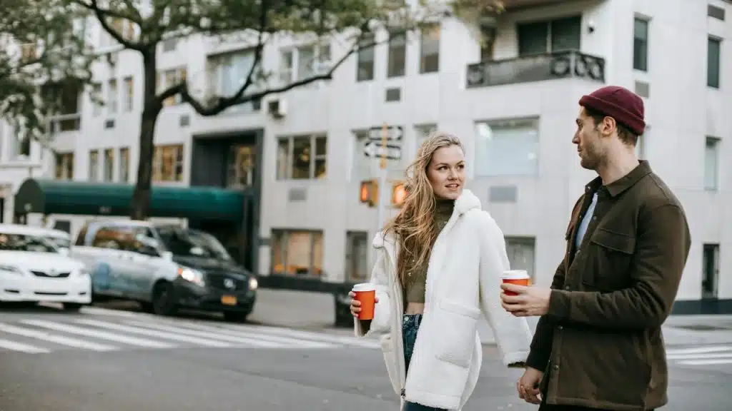 A couple walking in the city holding coffee cups.