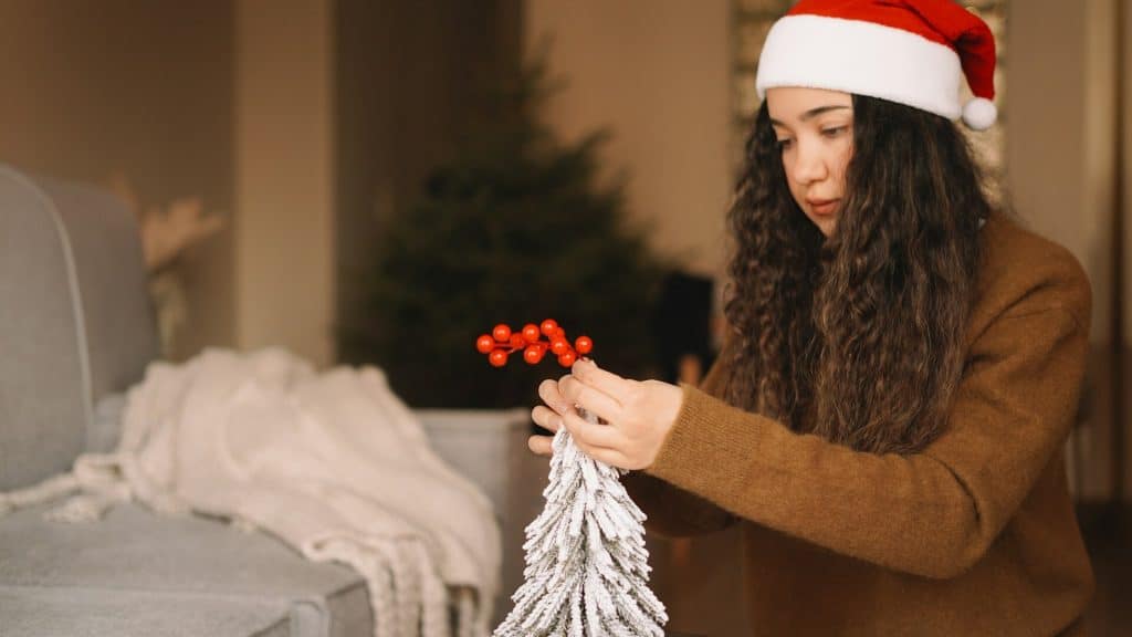 A woman decorating a small Christmas tree.