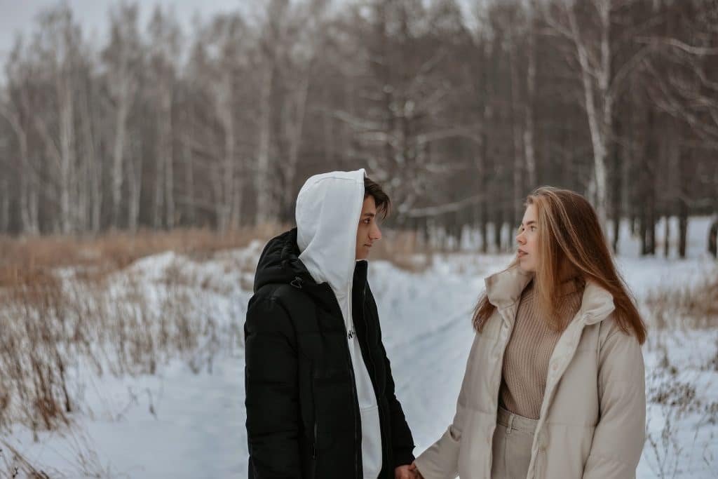 A couple holding hands in the snowy forest.