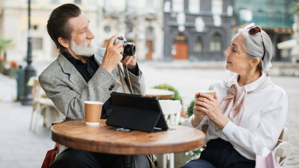 Mature bearded man using a retro camera for taking a photo of his pretty, lovely wife