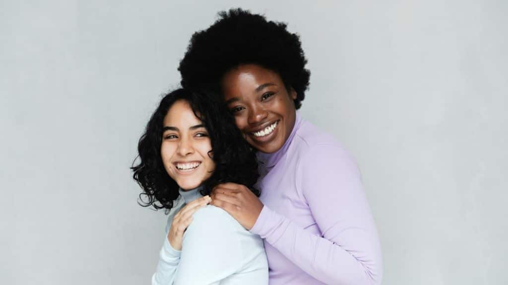 Two women hugging each other and smiling.