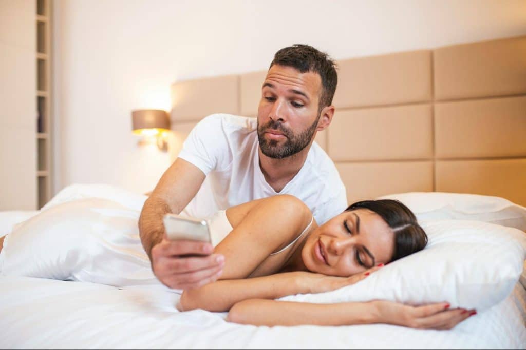 A woman sleeping and a man checking her phone 