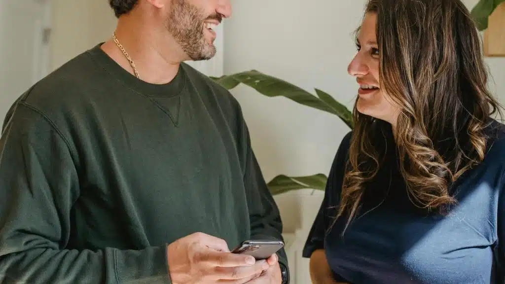 A man and woman smiling while talking indoors