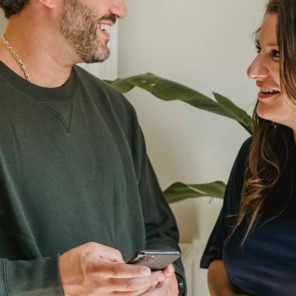 A man and woman smiling while talking indoors