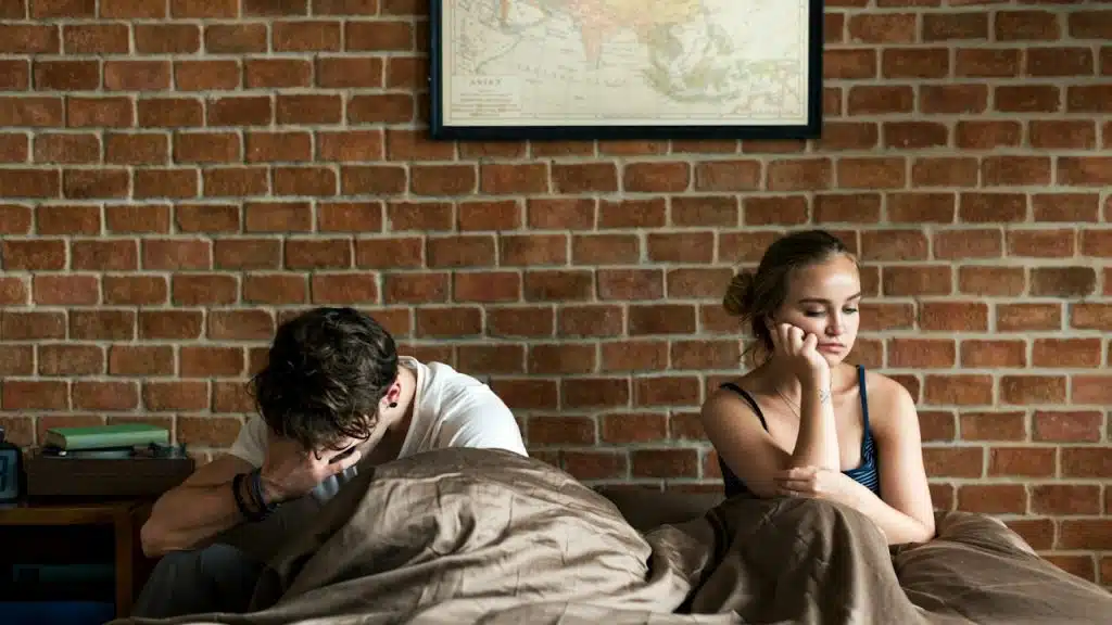An upset man and woman lying in bed.