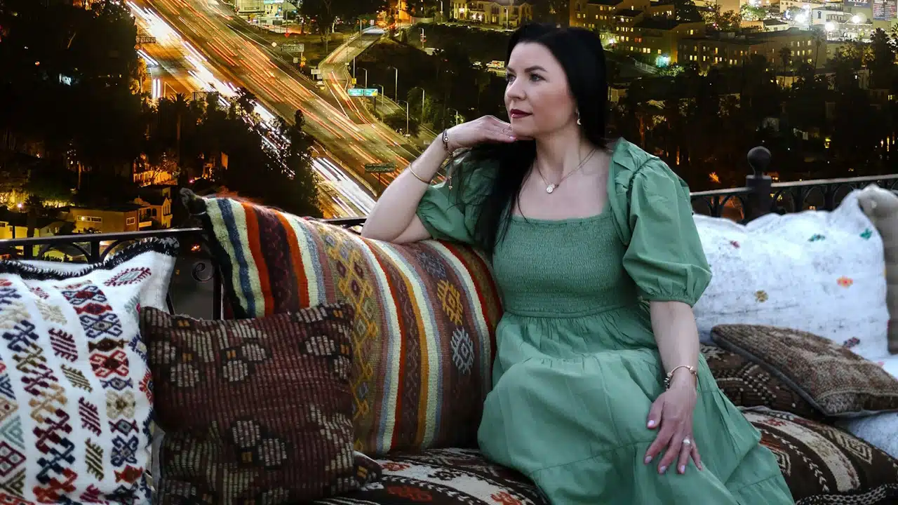 A woman is sitting on top of a couch in front of a city.