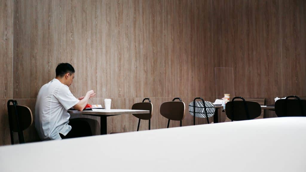 A man sitting alone at the corner of a fastfood chain.