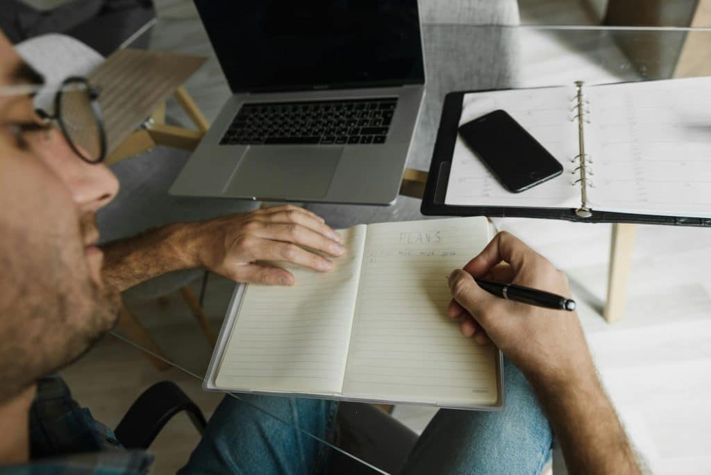 A man writing plans on his notebook.