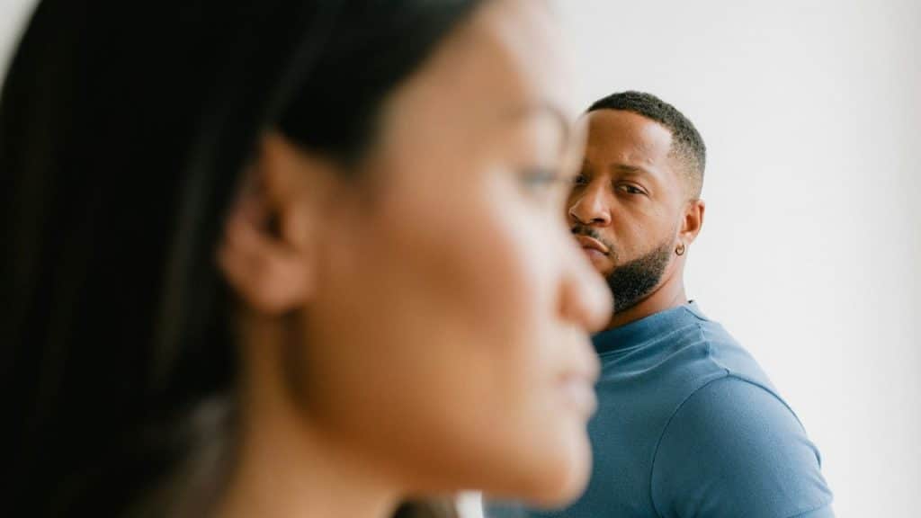 A blurred woman's face is in the foreground with a man looking over her shoulder.
