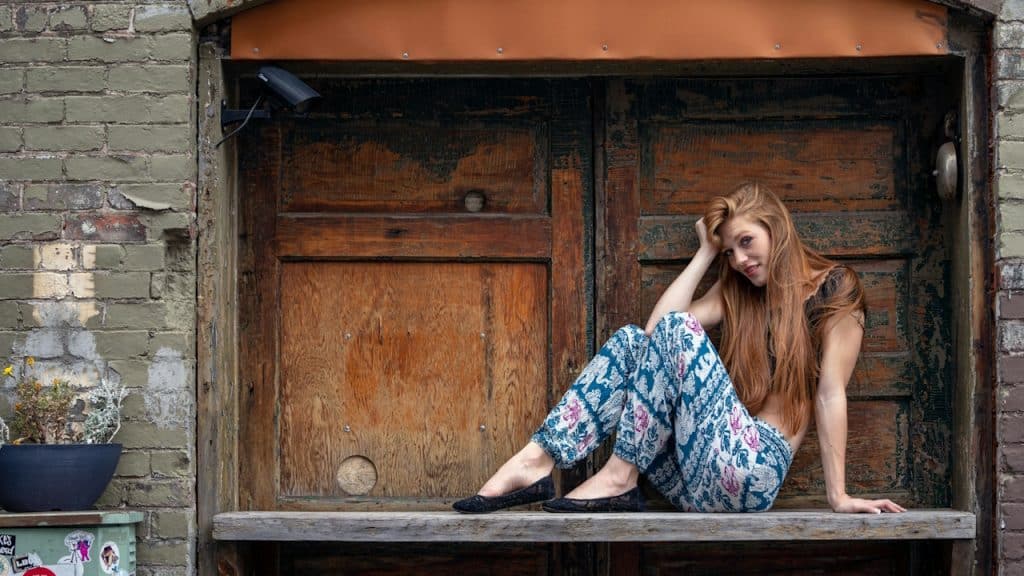A beautiful young woman sitting on top of a wooden bench.