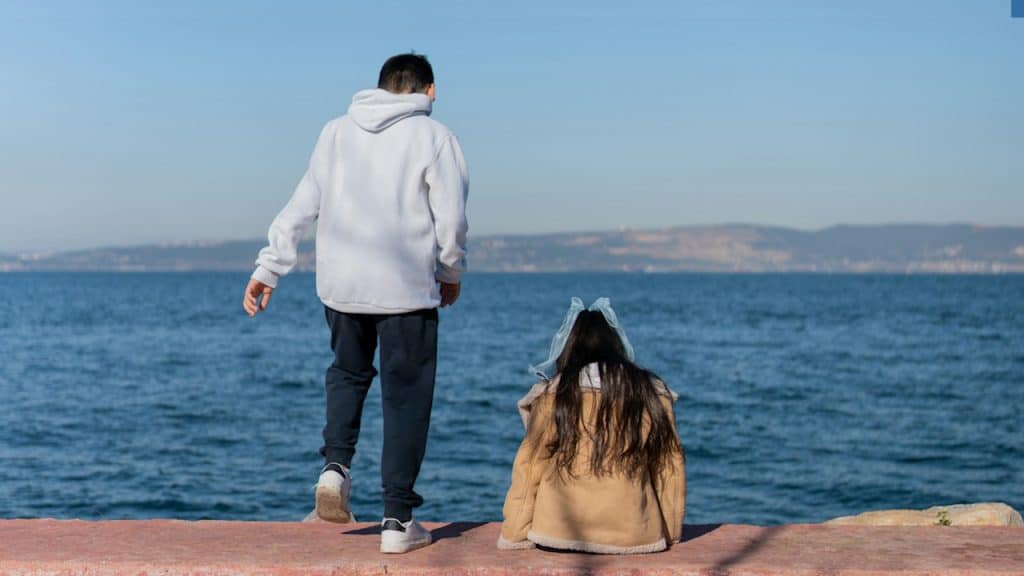A man standing on the edge of a pier next to a body of water.