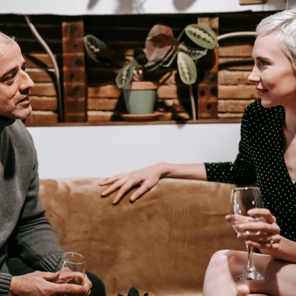 Couple sitting with wineglasses talking to each other