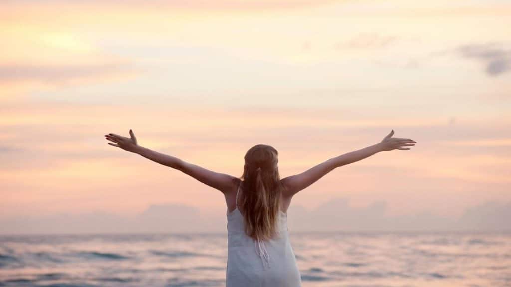 A woman with her arms raised at the beach