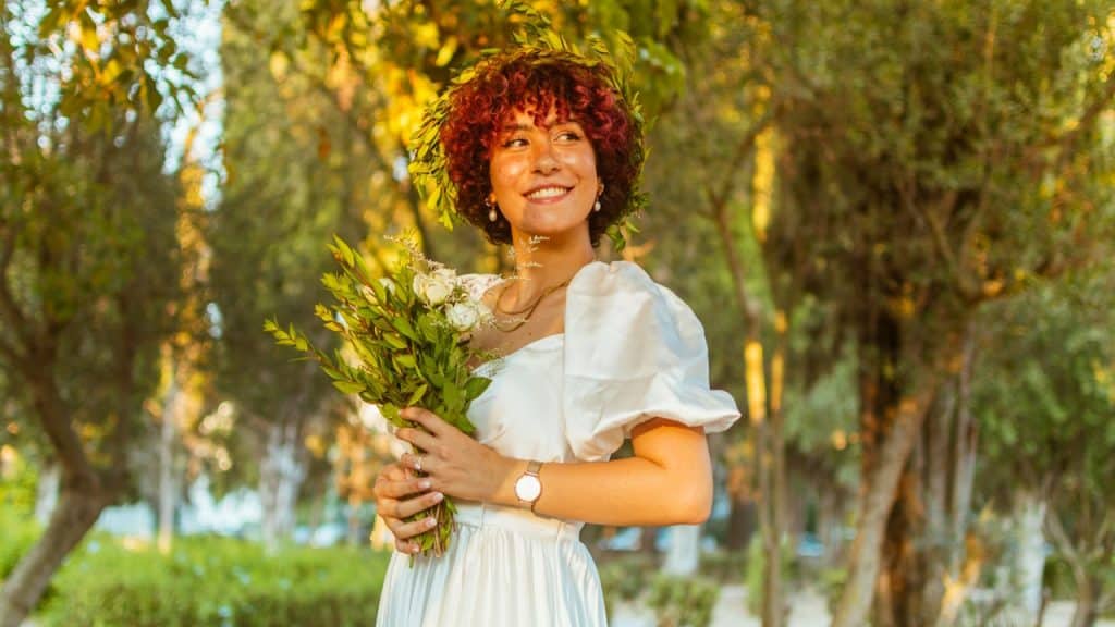 A woman holding flowers while standing in a park.