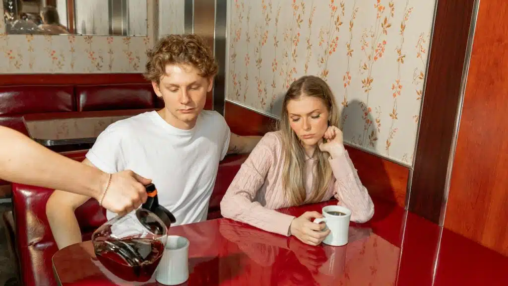A waiter pours coffee for a couple at a diner.