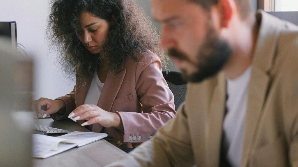 A woman typing at a desk beside a man working.