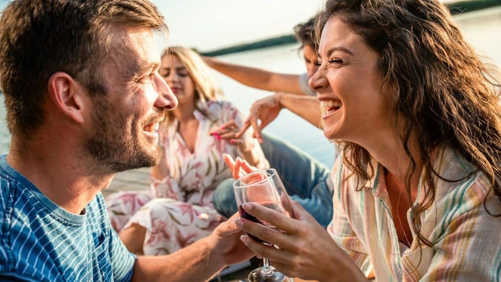 A group of people in a water boat laughing and drinking wine.