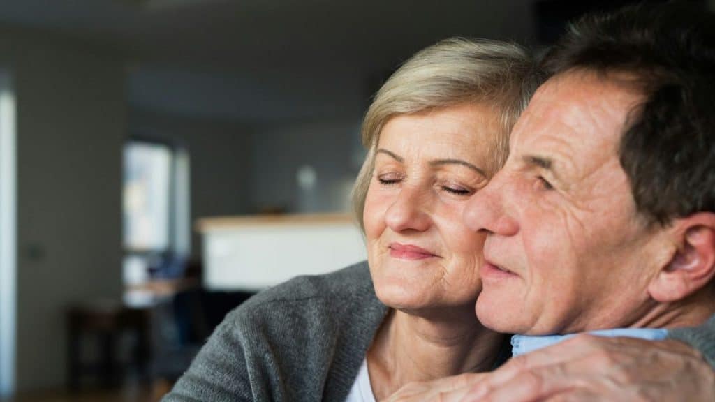 Close-up of a middle-aged woman hugging a man, smiling with her eyes closed.