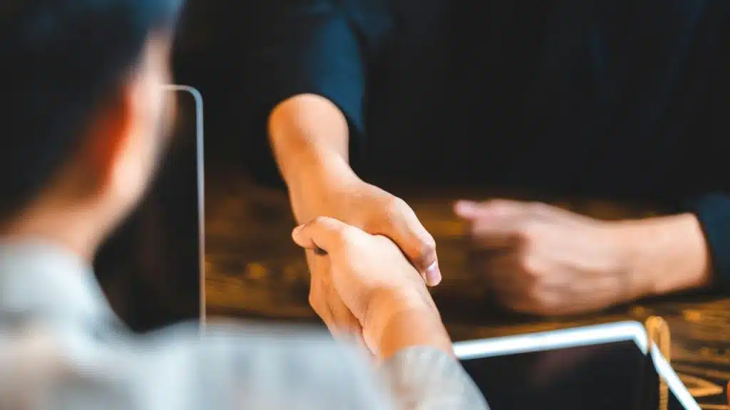 A close-up of two people shaking hands across a table.