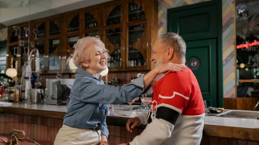 A senior couple sitting at a bar, laughing and enjoying each other’s company.